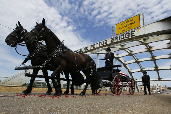 John Lewis casket on a horse drawn carriage passing under the Edmund Pettus Bridge