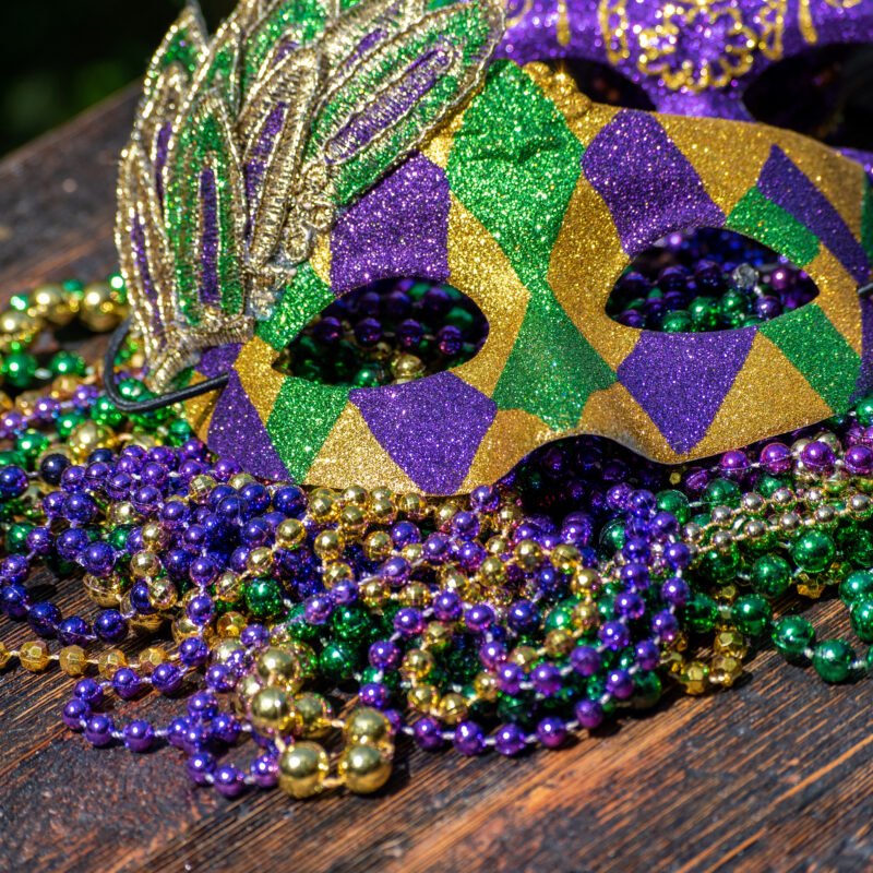 purple, green, and gold mardi gras mask and beads