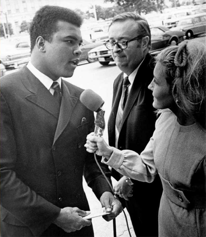 Charles Morgan Jr. standing beside Muhammad Ali as he's interviewed by a news reporter