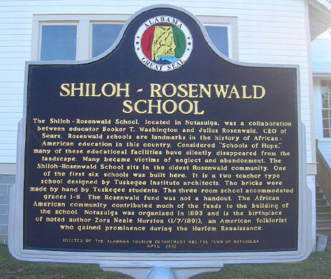 Shiloh-Rosenwald School historical marker. It states: "The Shiloh-Rosenwald School, located in Notasulga, was a collaboration between educator Booker T. Washington and Julius Rosenwald, CEO of Sears. Rosenwald schools are landmarks in the history of African-American education in this country. Considered "Schools of Hope," many of these educational facilities have silently disappeared from the landscape. Many became victims of neglect and abandonment. The Shiloh-Rosenwald School sits in the oldest Rosenwald community. One of the first six schools was built here. It is a two-teacher type school designed by Tuskegee Institute architects. The bricks were made by hand by Tuskegee students. The three-room school accommodated grades 1-8. The Rosenwald fund was not a handout. The African American community contributed much of the funds to the building of the school. Notasulga was organized in 1893 and is the birthplace of noted author Zora Neale Hurston (1/7/1891), an American folklorist who gained prominence during the Harlem Renaissance. Erected by the Alabama Tourism Department and the Town of Notasulga. April 2010."