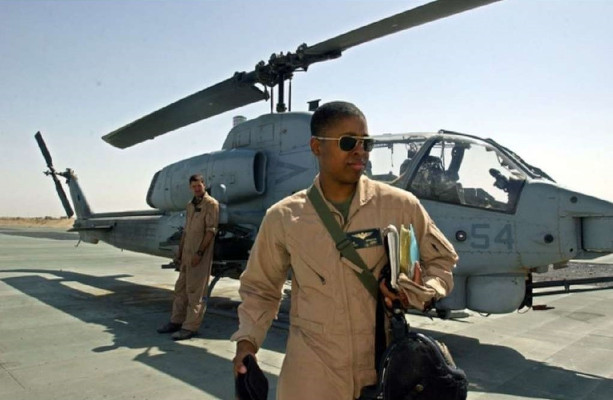 Black female aviator Captain Vernice Armour walking on a landing strip in front of a military helicopter