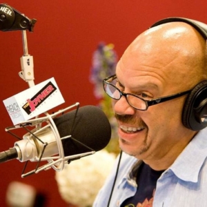 Tom Joyner talking into the microphone at radio station