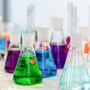 A group of Erlenmeyer flasks containing different colors of liquid