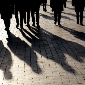 Lower half of a group of indistinguishable people walking on a bricked path